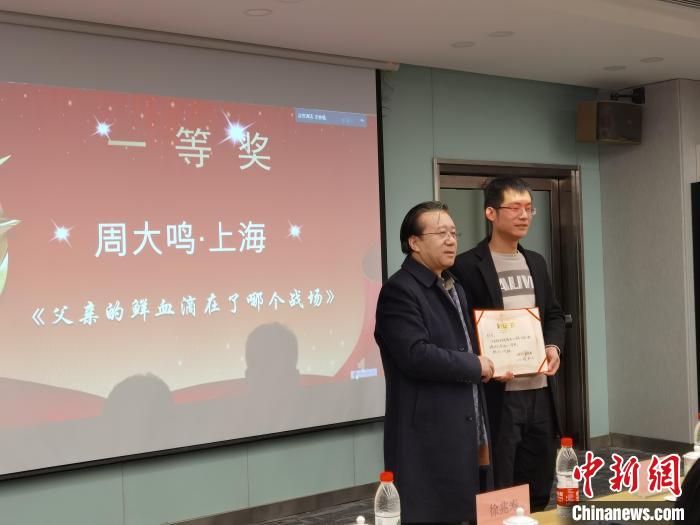 圖為作家、西北師范大學(xué)新聞與傳媒學(xué)院院長徐兆壽頒發(fā)一等獎證書，代領(lǐng)獎?wù)呱吓_領(lǐng)獎。　楊娜 攝
