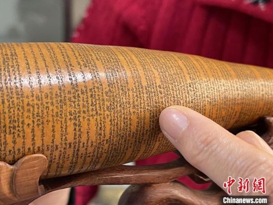 圖為長(zhǎng)約二十公分的長(zhǎng)條葫蘆雕刻佛教經(jīng)文作品?！堟?攝