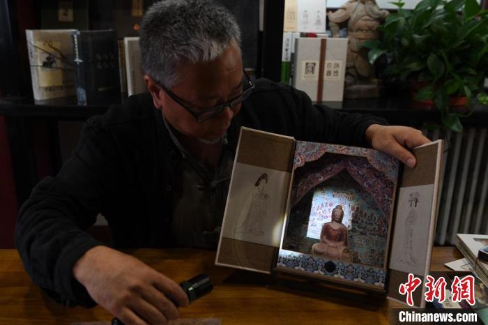 圖為讀者出版集團(tuán)讀者晉林工作室獨(dú)立出品人徐晉林，展示互動(dòng)性強(qiáng)的敦煌題材手工書(shū)。(資料圖) 楊艷敏 攝