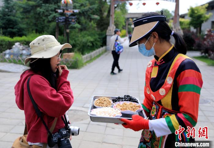 圖為身穿土族服飾的女性介紹當(dāng)?shù)靥厣〕??！⊙Φ?攝